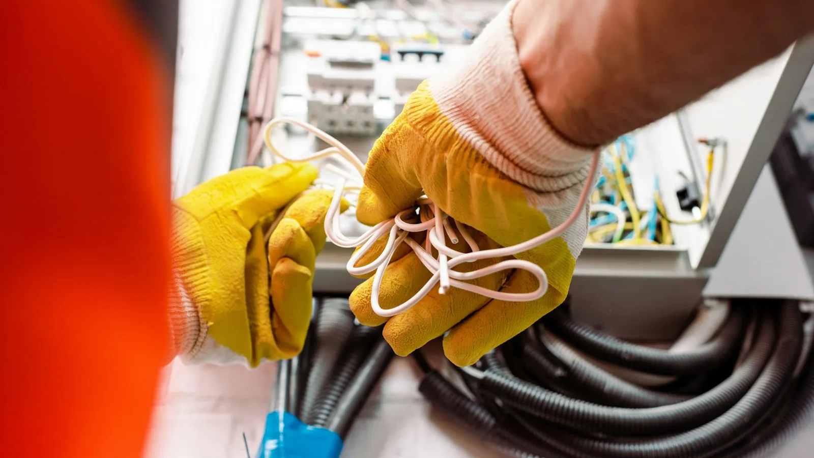 Electricista con guantes aislantes revisando un cuadro eléctrico